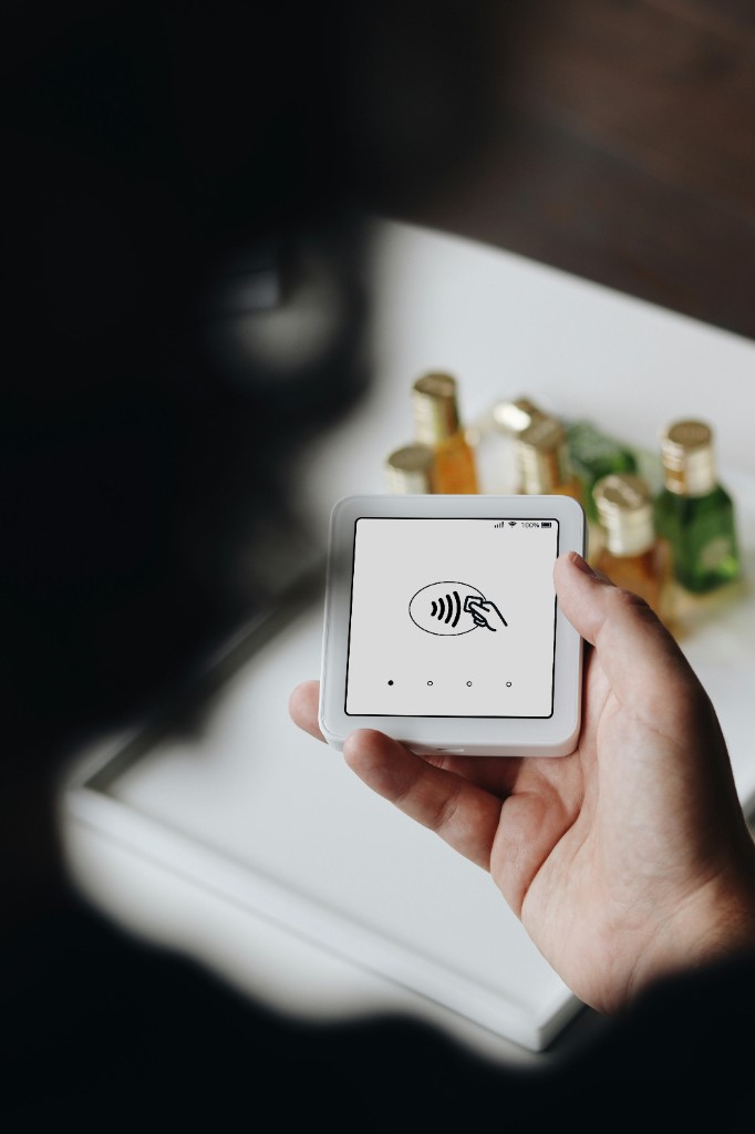 Hand holding a contactless payment terminal at checkout